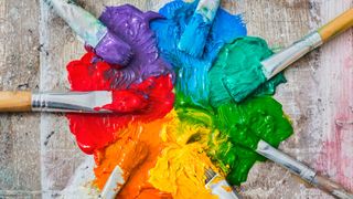 Various brushes being coated in oil paint on canvas