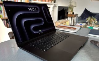 A Space Black Apple MacBook Pro 16-inch M3 sitting on a grey/blue table