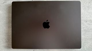 A Space Black Apple MacBook Pro 16-inch M3 sitting on a grey/blue table