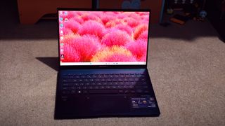 A blue ASUS Zenbook 14 OLED (UX3405) on a carpeted floor