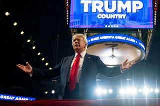 Donald Trump stands in front of Make America Great sign