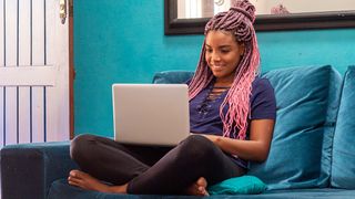 A black woman sits on a sofa and uses a one of the best laptops for battery life