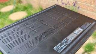 A black ASUS ProArt P16 laptop sitting on stone paving