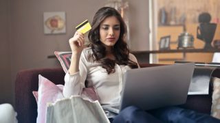 Woman at laptop waving credit card