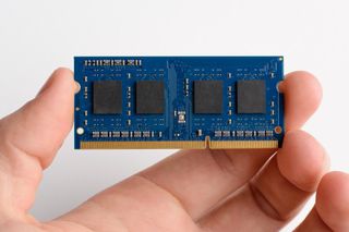 A hand holding a RAM chip used to upgrade laptop