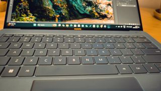 A blue Huawei Matebook X Pro laptop on a wooden desk, in front of blue and orange LED lights.