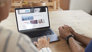 Two people look over an open laptop that's showing a website builder.