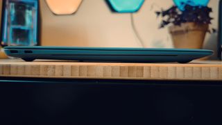 A blue Huawei Matebook X Pro laptop on a wooden desk, in front of blue and orange LED lights.