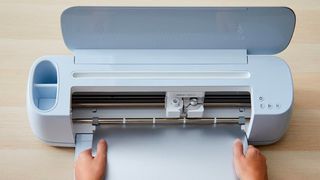 Cricut Explore 3 vs Cricut Maker 3; a maker 3 craft machine being fed paper