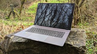 Silver MSI Creator Z17 sitting on a stone bench in a forest setting