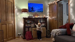 A toddle looks up at the wall-mounted Frame TV in a living room.